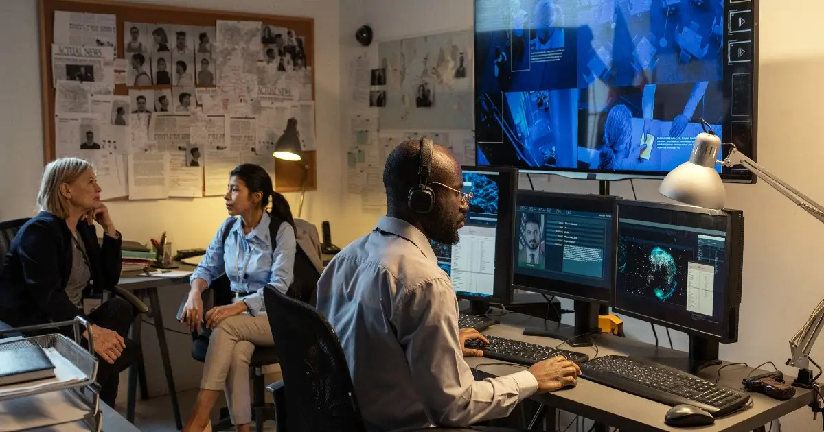 African-American-FBI-agent-sitting-in-front-of-computer-monitors-and-screen.jpeg